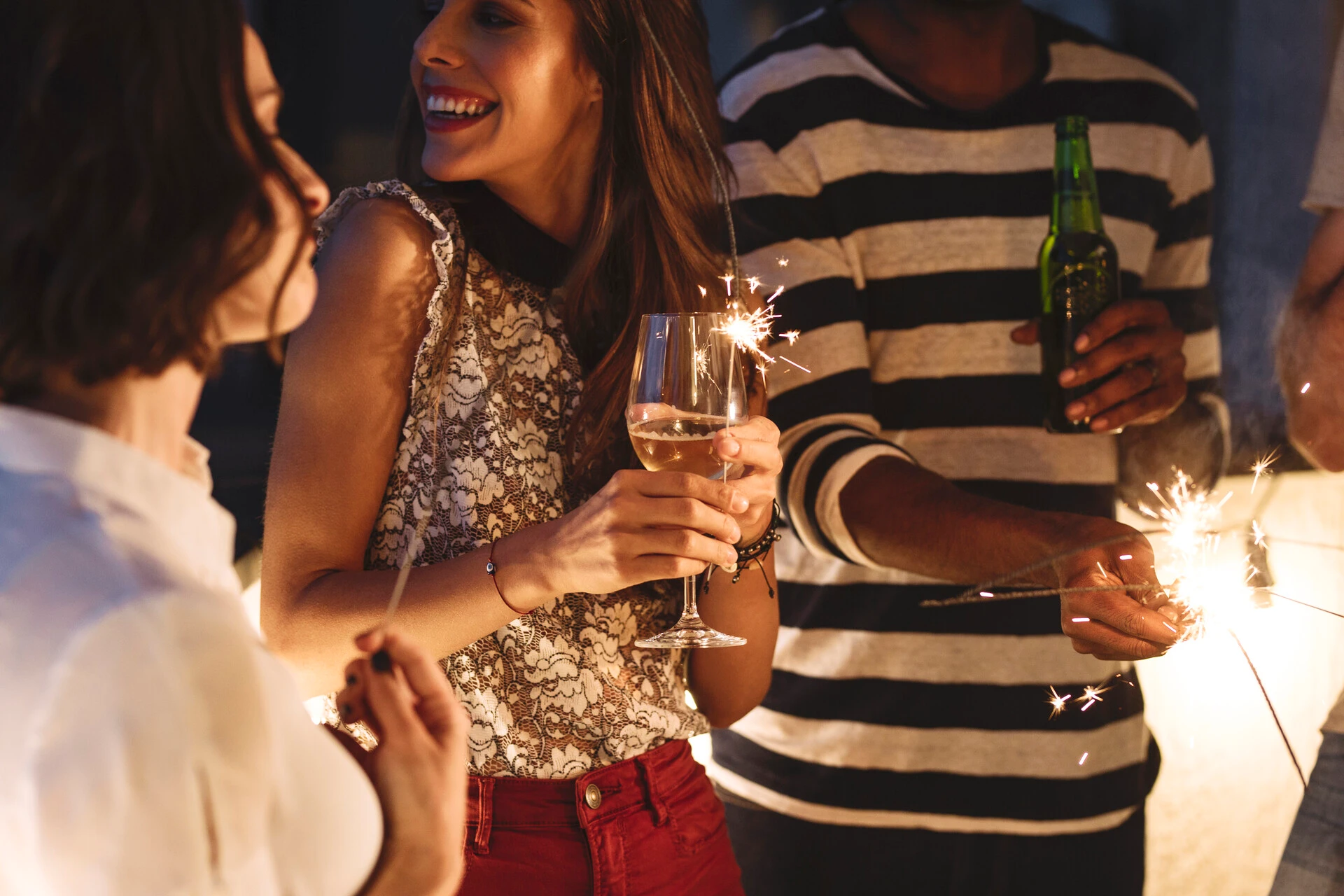 Friends celebrating with sparklers and drinks at night