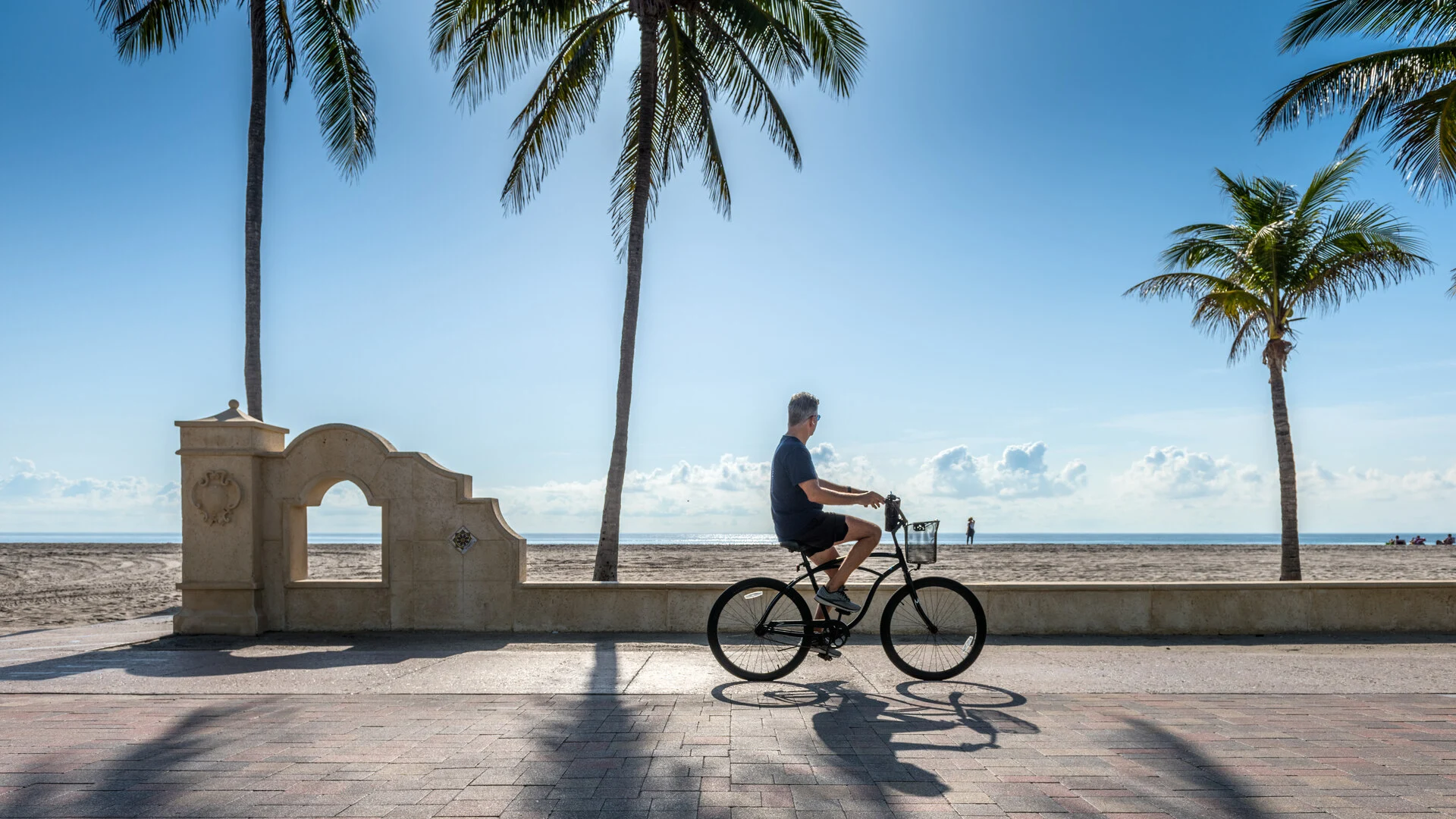 Man riding a bike along a beachside path
