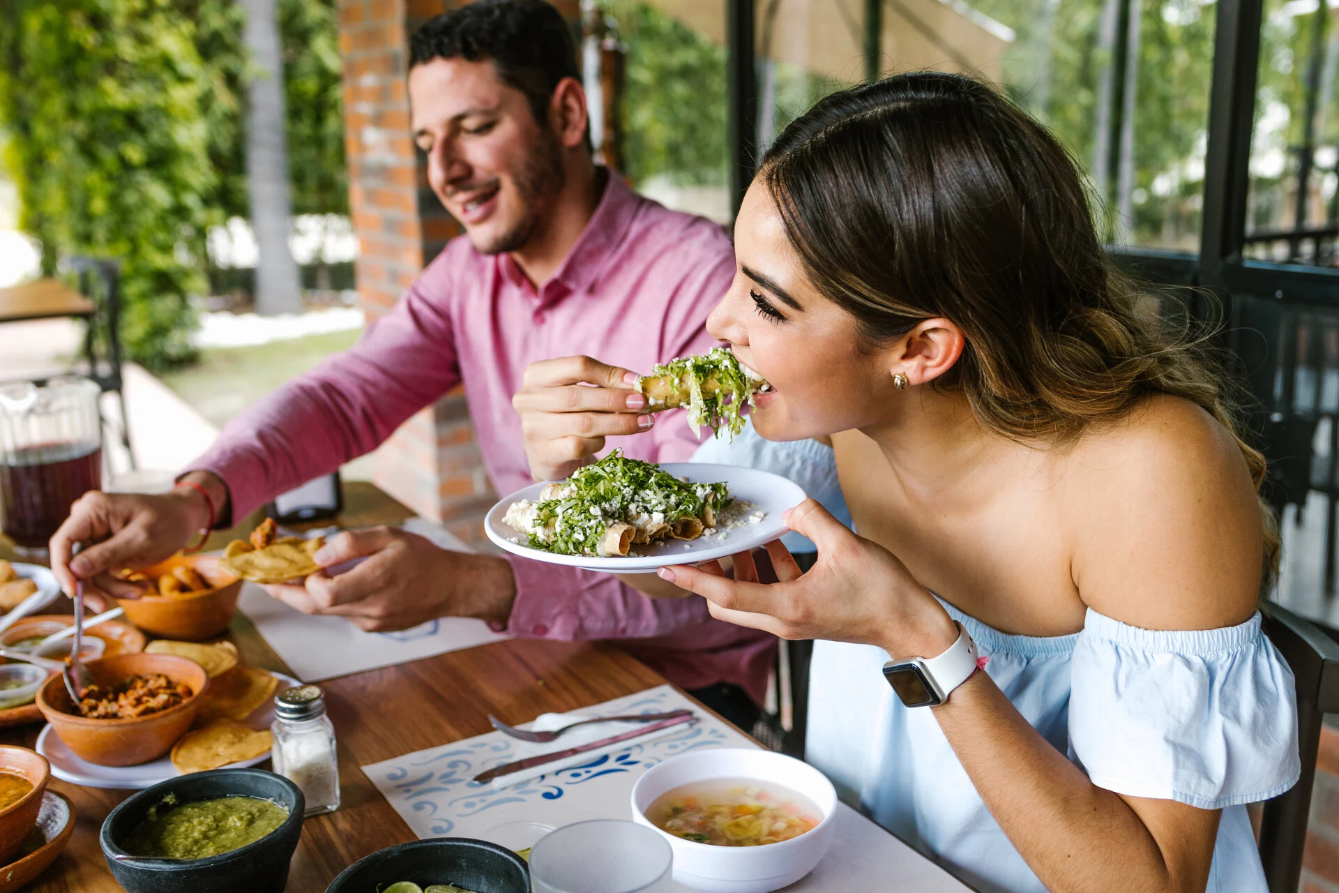 Woman enjoying tacos at an outdoor restaurant with a friend